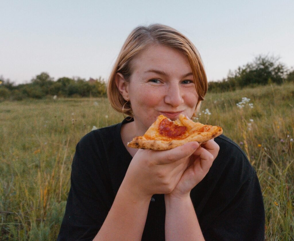 mujer comiendo pizza feliz,reconciliada con la comida nutricionista online